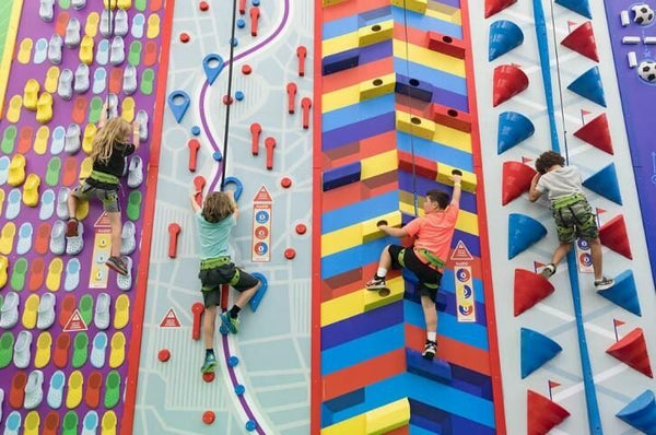 4 kids climbing a rock wall