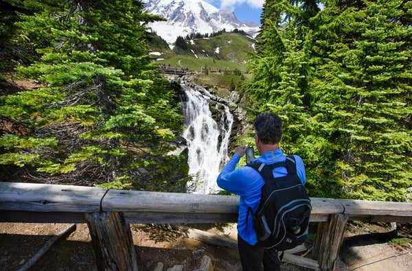 Man taking photo of waterfall