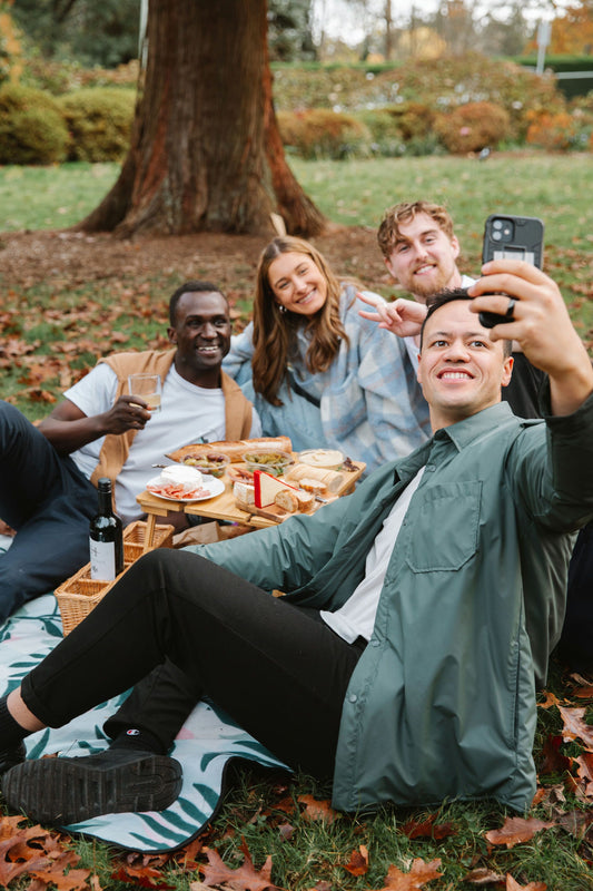 four adults eating picnic and taking photo