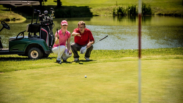 man and woman learning golf