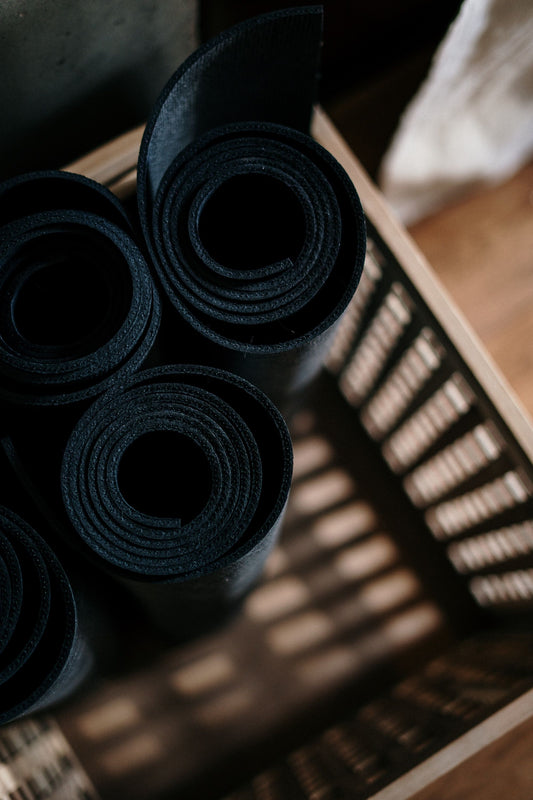 woman stretching on a grey mat in a yoga class